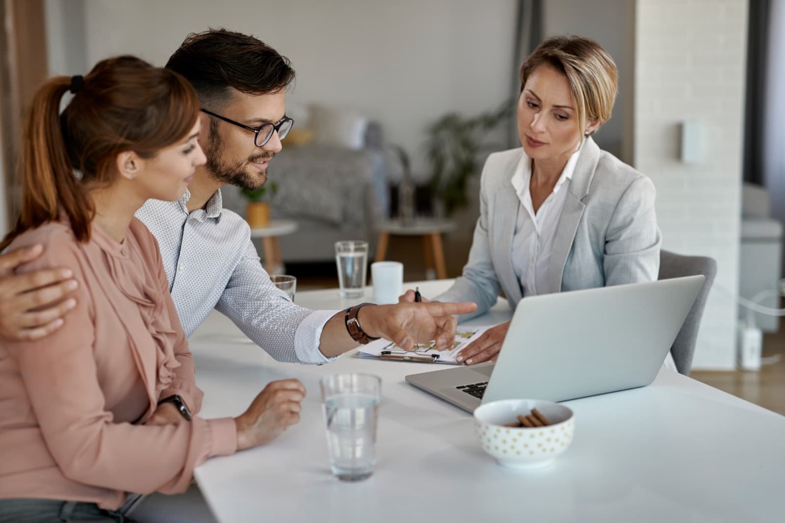 Un couple fait le point sur ses projets autour d'une table, documents et ordinateur portable ouverts.