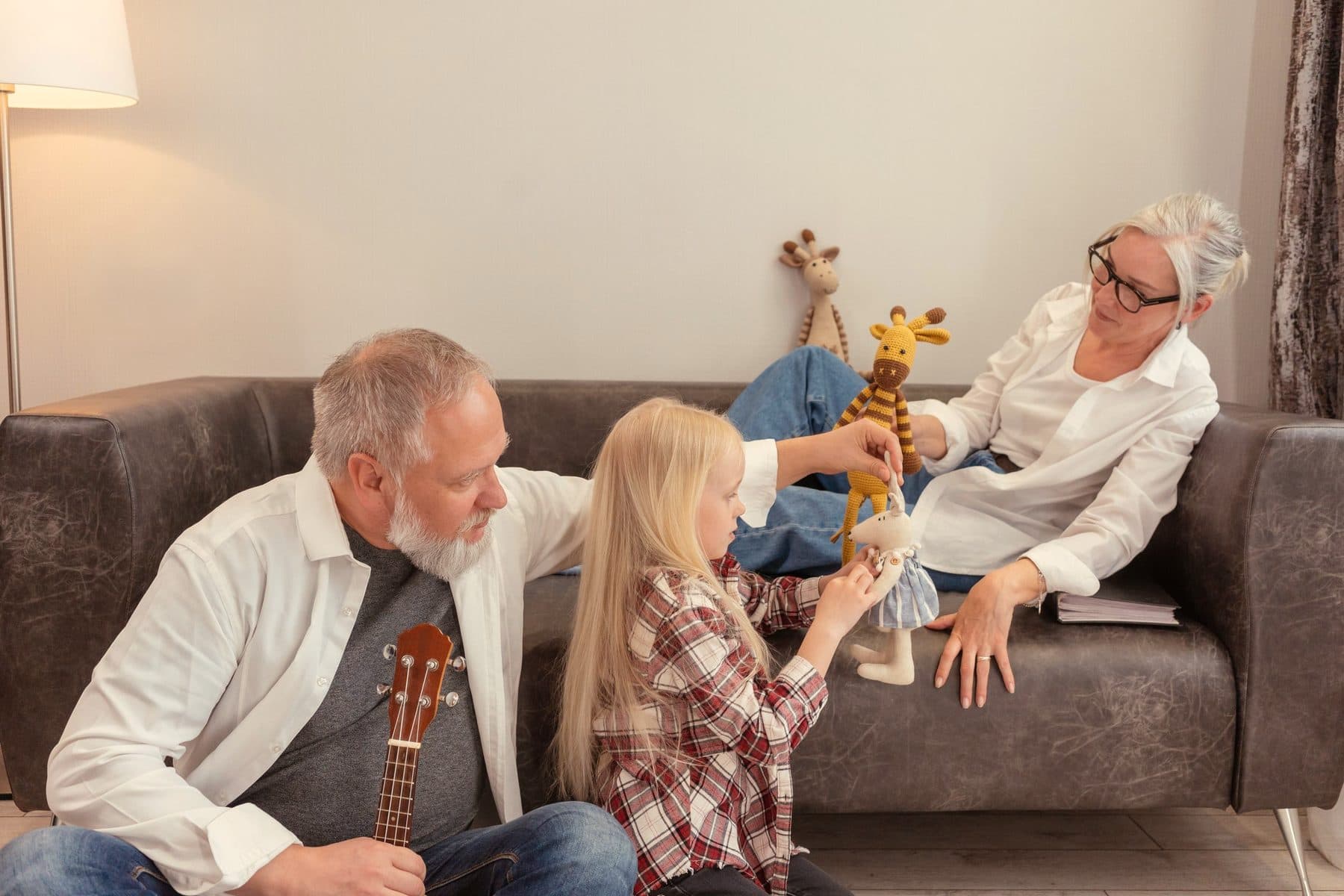 Des grands-parents jouent avec leur petite-fille dans leur salon.