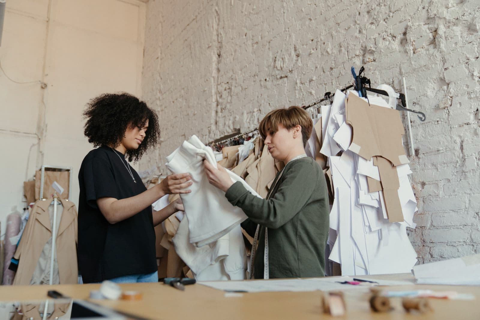 Deux femmes ajustent un vêtement dans un atelier de couture.
