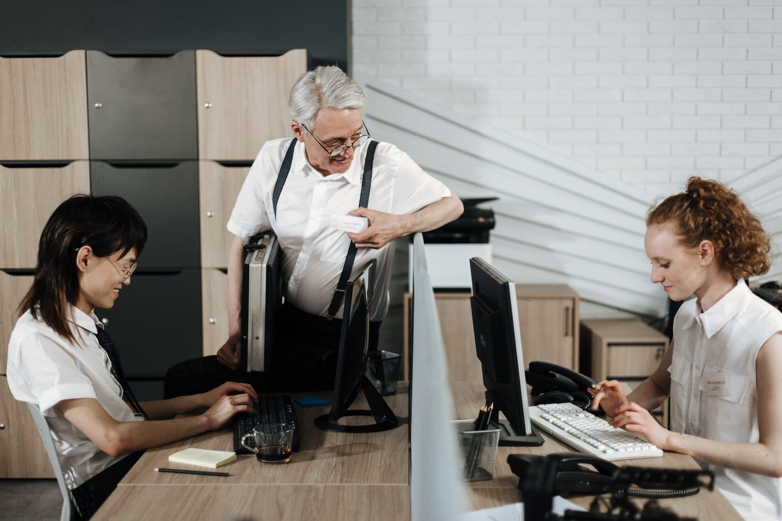 Un salarié expérimenté échange avec deux jeunes collègues installées à leur poste de travail.