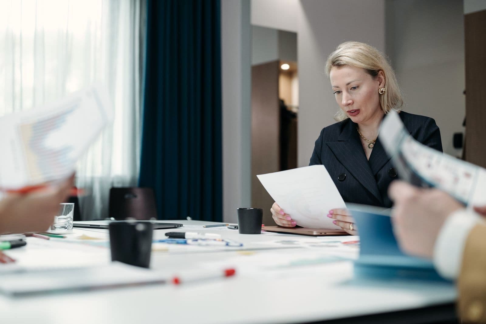 Une dirigeante relit des documents à une table de réunion.