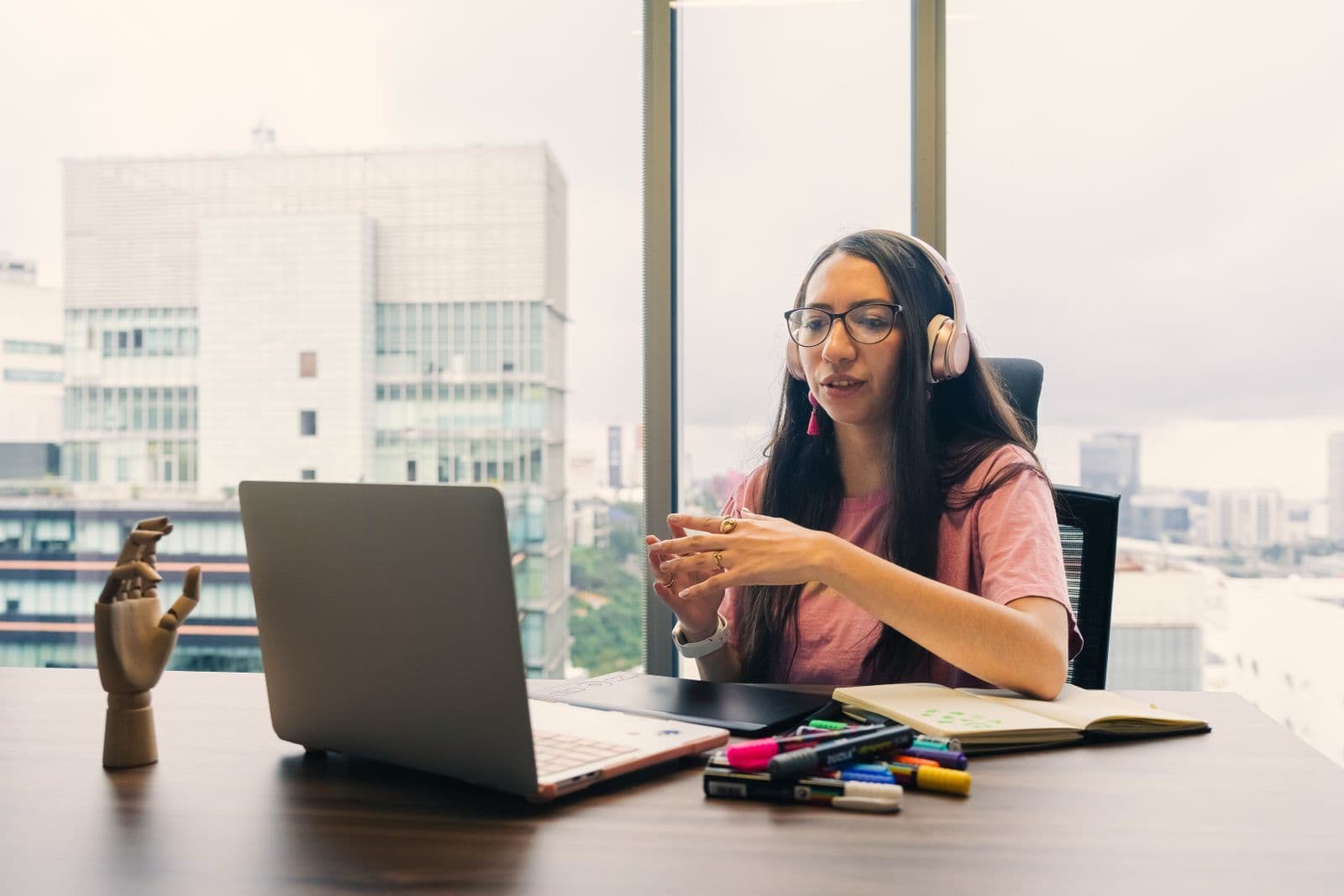 Une cheffe d'entreprise échange en visio depuis son bureau, casque sur les oreilles.