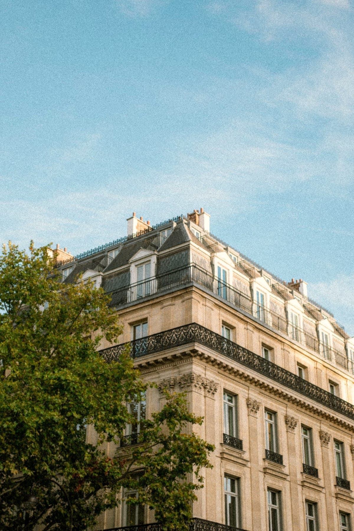 Une façade d'immeuble haussmannien à Paris, sous un ciel bleu.