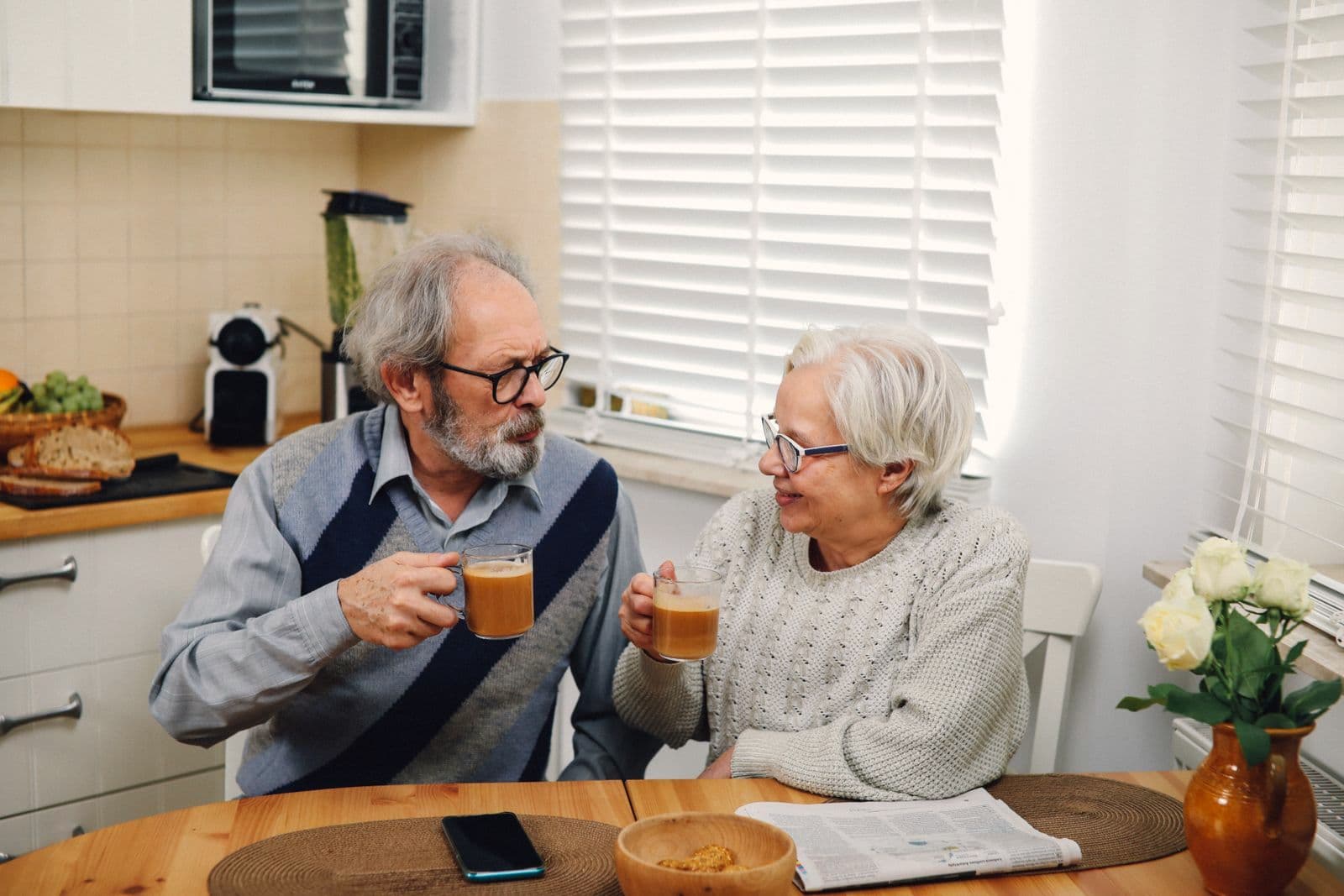 Un couple de retraités prend un café ensemble à la table de sa cuisine.