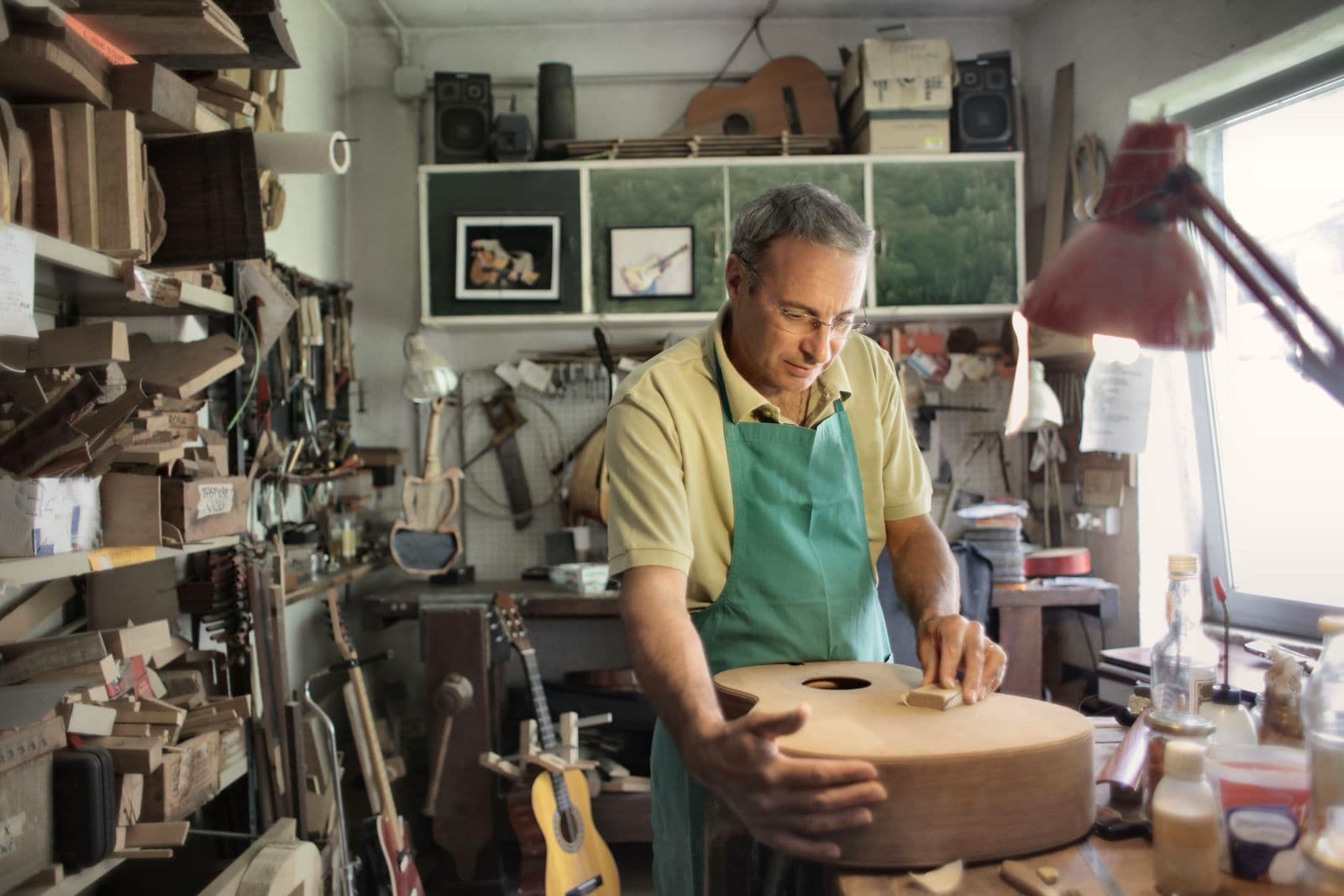 Un artisan luthier ponce une caisse de guitare dans son atelier.