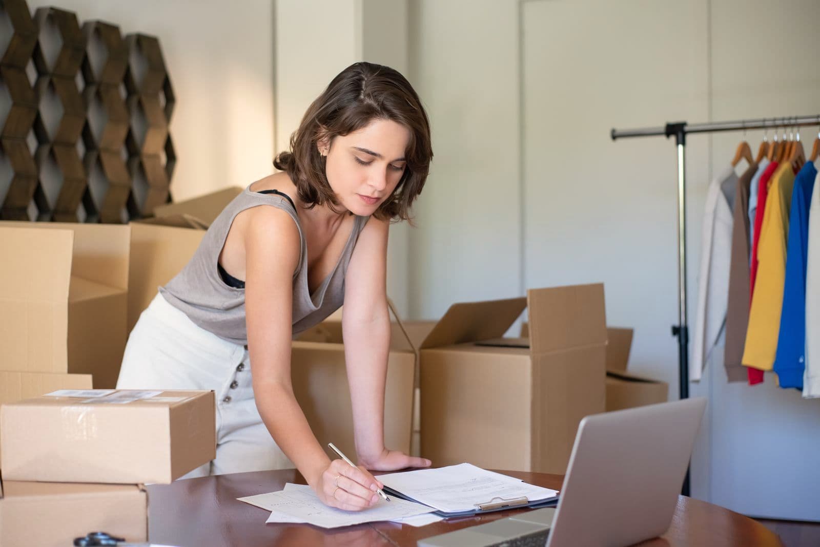 Une cheffe d'entreprise prend des notes au milieu des cartons de sa réserve.