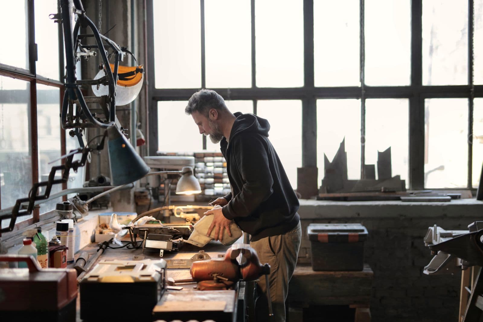 Un artisan travaille à son établi, dans un atelier baigné de lumière naturelle.